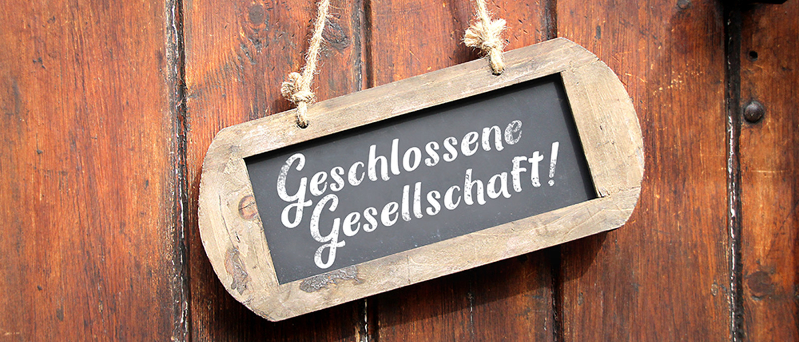 Schild mit der Aufschrift 'Geschlossene Gesellschaft' an einer Holztür.